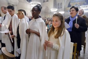 26 mars 2016 : Les nouveaux baptisés sont revêtus du vêtement blanc et portent la lumière pascale, lors de la célébration de la Vigile pascale. Paroisse Saint Ferdinand des Ternes, Paris (75), France.