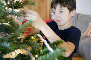 13 décembre 2017 : Garçon de 10 ans décorant un sapin de Noël. France.